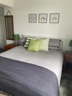 a bedroom with a large white bed with green pillows at Newquay Beachcomber 2 Bedroom Apartment in Saint Columb Minor