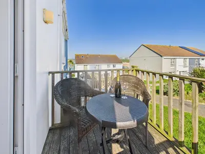 a patio with a table and chairs on a balcony at Surf View by Signature Stays - Pool - Beach Access in Crantock