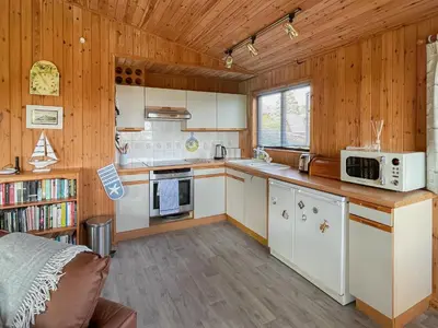 a kitchen with white cabinets and wooden walls at The Hut Hotel in Falmouth