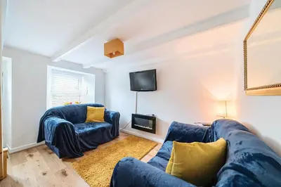 a living room with two blue couches and a tv at Charming Chardan Cottage, Fowey in Fowey