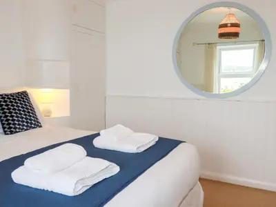 a bedroom with a bed with a mirror and towels at Nanvivian in Feock