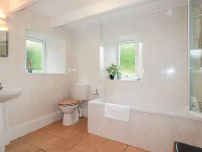 a bathroom with a tub and a toilet and a sink at Nanvivian in Feock
