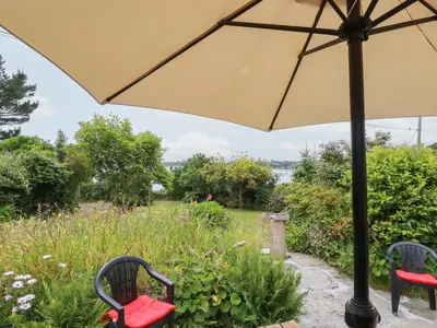 a patio with two chairs and an umbrella at Nanvivian in Feock