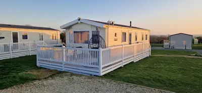 a large yellow house with a white fence at HolidayLet 24 Bude Newperran Holiday Park in Cubert