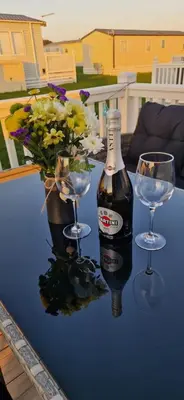 a bottle of wine and two glasses on a table at HolidayLet 24 Bude Newperran Holiday Park in Cubert