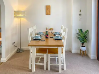 a dining room table with white chairs and a table and a lamp at Chy An Mordros in Hayle