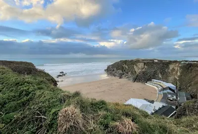 a sandy beach with chairs and the ocean at 32 One Lusty Glaze in Newquay in Newquay
