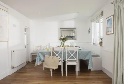 a white dining room with a blue table and chairs at Tresevens in Polzeath