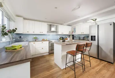 a kitchen with white cabinets and a stainless steel refrigerator at Tresevens in Polzeath