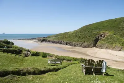 two chairs and a bench sitting on top of a beach at The Perch Studio in Polzeath