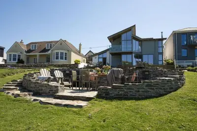 a backyard with a table and chairs on a rock wall at The Perch Studio in Polzeath
