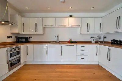 a white kitchen with wooden floors and white cabinets at Finest Retreats - Jubilee Cottage at Bodmin Moor in Saint Breward
