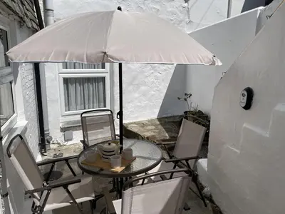 a table and chairs under an umbrella on a balcony at Morvah - stunning views of the harbour and beyond in St Ives