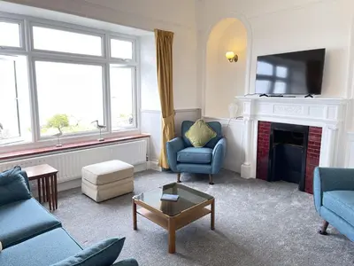 a living room with blue chairs and a fireplace at Morvah - stunning views of the harbour and beyond in St Ives