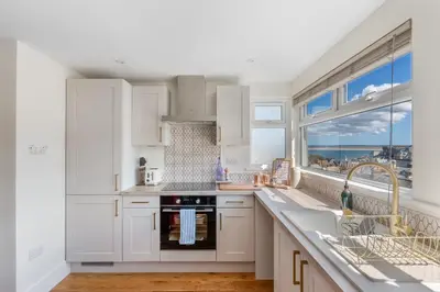 a kitchen with white cabinets and a view of the ocean at High Tide Bedford Rd Boutiques in St Ives