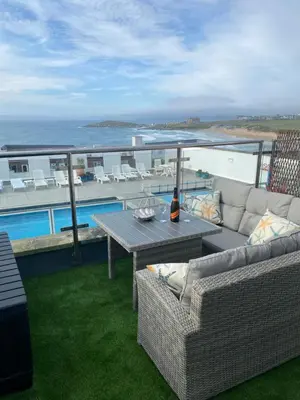 a patio with a couch and a table on a balcony at Stunning Sea View Apartment in Newquay with 2 Heated Pools in Crantock