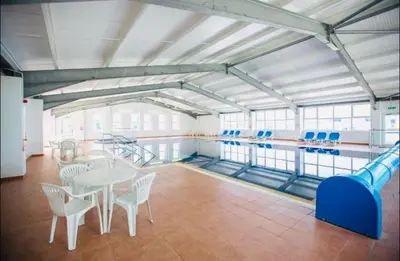 a swimming pool with a table and chairs in a room at Sea Breeze Escape in Cubert