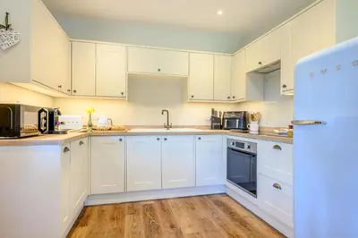 a white kitchen with white appliances and wooden floors at 2 Bed in Altarnun oc-t31858 in Altarnun