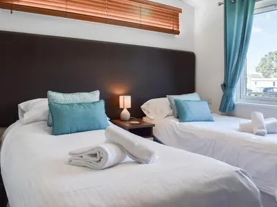 two beds with towels on them in a bedroom at Sunshine Lodge in Polperro