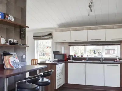 a kitchen with white cabinets and a counter with stools at Sunshine Lodge in Polperro