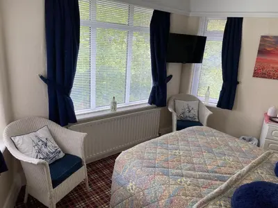 a bedroom with a bed and two chairs and a window at Cornerways Guest House St Austell Cornwall in St Austell