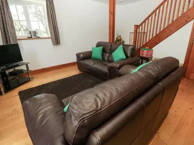 a living room with a leather couch and a television at The Stable Barn in Hayle