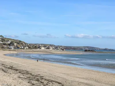 a beach with a person walking on the sand at The Coach House in Hayle