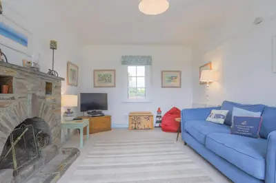 a living room with a blue couch and a fireplace at Trewidden in Polzeath