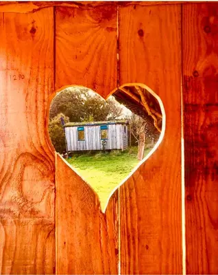 a heart shaped picture of a house on a wooden fence at Wrens Nest in Saint Mabyn
