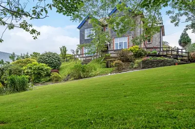 a house on a hill with a green lawn at Boscastle House in Boscastle