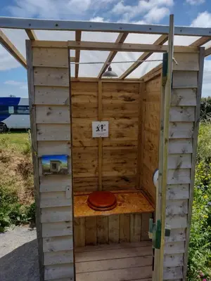 a wooden outhouse with a toilet in it at Celtic Longhouse Tent at Coverack Camping in Coverack