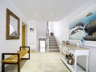 a hallway with a table and a bench and a staircase at 11 Slipway in Padstow