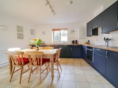a kitchen with blue cabinets and a table and chairs at Casa Piedra in Polzeath