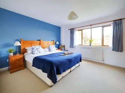 a blue bedroom with a bed and a window at Casa Piedra in Polzeath