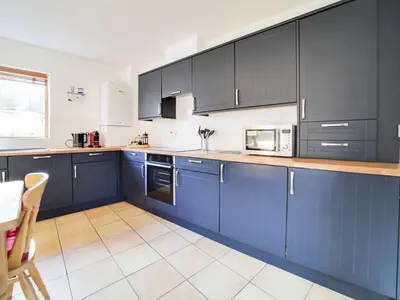 a large kitchen with blue cabinets and a table at Casa Piedra in Polzeath