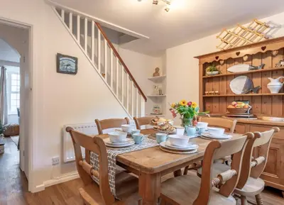 a dining room with a wooden table and chairs at Charming Fishing Cottage in Polruan