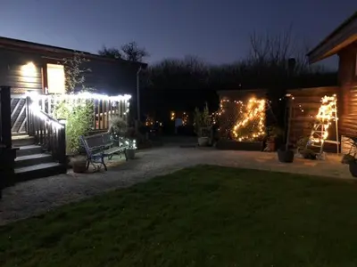 a backyard at night with lights on a fence at Sunset family lodge private garden private parking in Saint Columb Minor