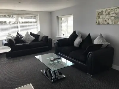 a living room with two black couches and a glass table at Pencarrick in Kenwyn