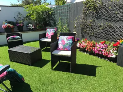 three chairs and a table in a garden with flowers at Pencarrick in Kenwyn