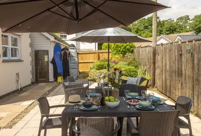 a table and chairs with an umbrella on a patio at Puffin Way in Hayle