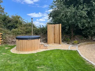 a garden with a trash can in the grass at Kilden Hut - Perranwell Station in Perranwell