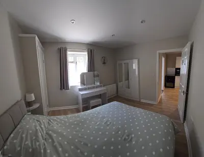 a bedroom with a bed and a desk and a window at Acklington 2 bedroom property in Menheniot