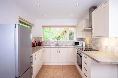 a kitchen with white cabinets and a large window at Creek View in Feock