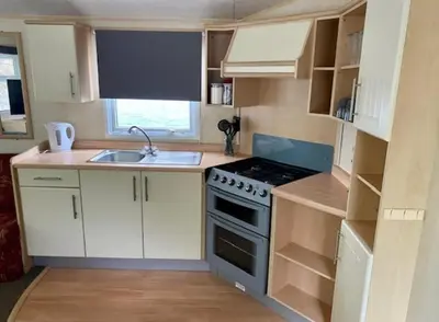 a small kitchen with a stove and a sink at Cabin by Beach & Nature Reserve Mon & Fri Check in Days Swanpool Falmouth Cornwall in Falmouth