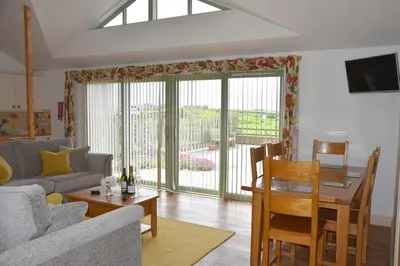 a living room with a couch and a dining room at Willow Beautiful 3 bed accessible holiday cottages in Tregoney