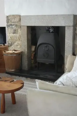 a stone fireplace with a stove in a living room at Dunlin Cottage in Penryn