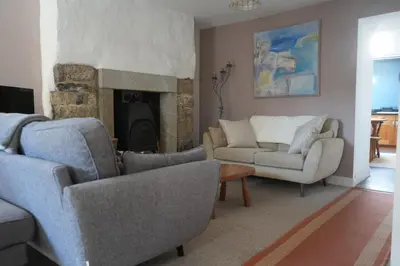 a living room with a couch and chairs and a fireplace at Dunlin Cottage in Penryn