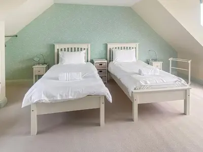 two beds with white sheets and pillows in a room at Coastguards in Porthscatho