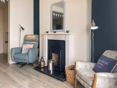 a living room with a chair and a fireplace at Coastguards in Porthscatho
