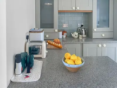 a kitchen with a bowl of fruit on a counter at Coastguards in Porthscatho